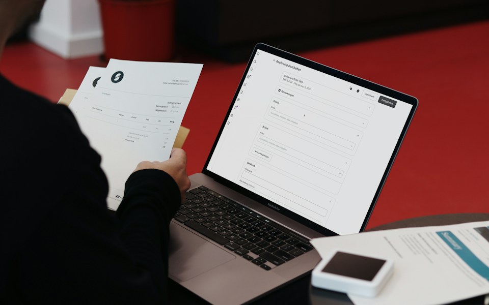 Persona revisando un comprobante en papel junto a un sistema de facturación en línea